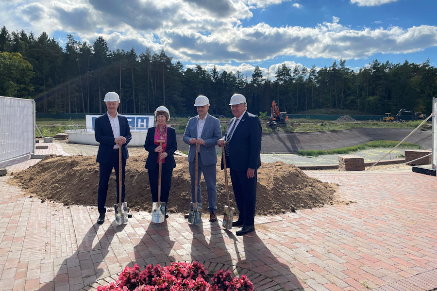 Vier Personen stehen mit einem Spaten auf einer Bauststelle Vier Personen stehen mit einem Spaten auf einer Bauststelle