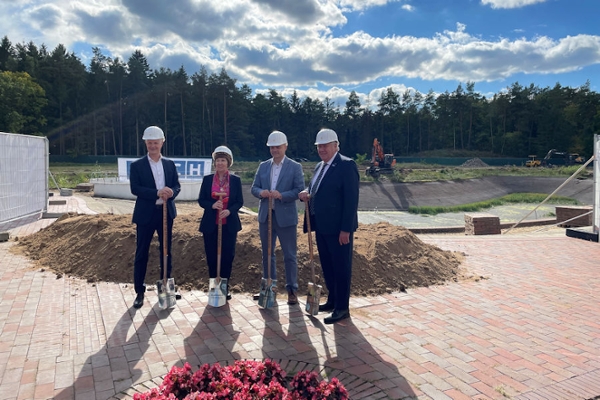 Vier Personen stehen mit einem Spaten auf einer Bauststelle Vier Personen stehen mit einem Spaten auf einer Bauststelle